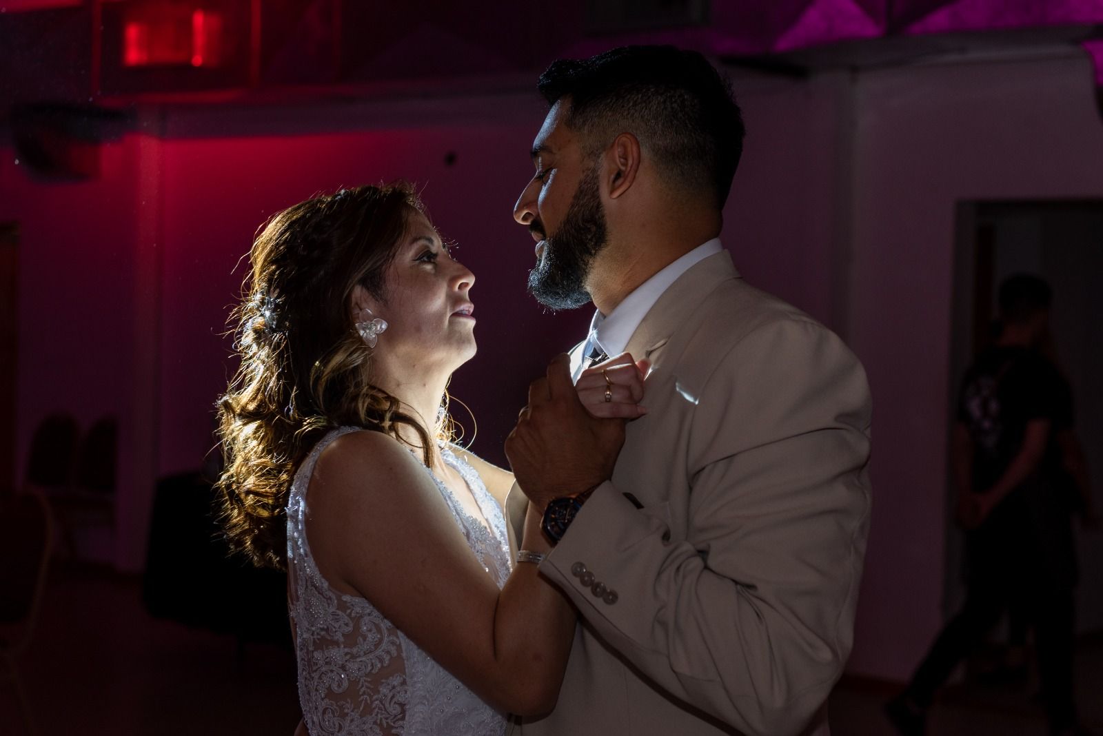 Pareja bailando en la recepción de la boda, iluminada en rosa y contraluz.
