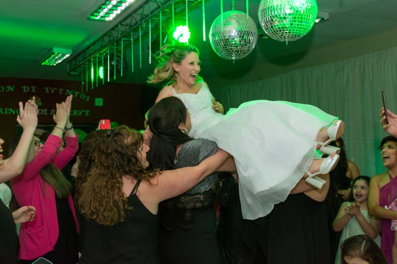 Una novia es alzada en el aire por sus amigos en una fiesta. 