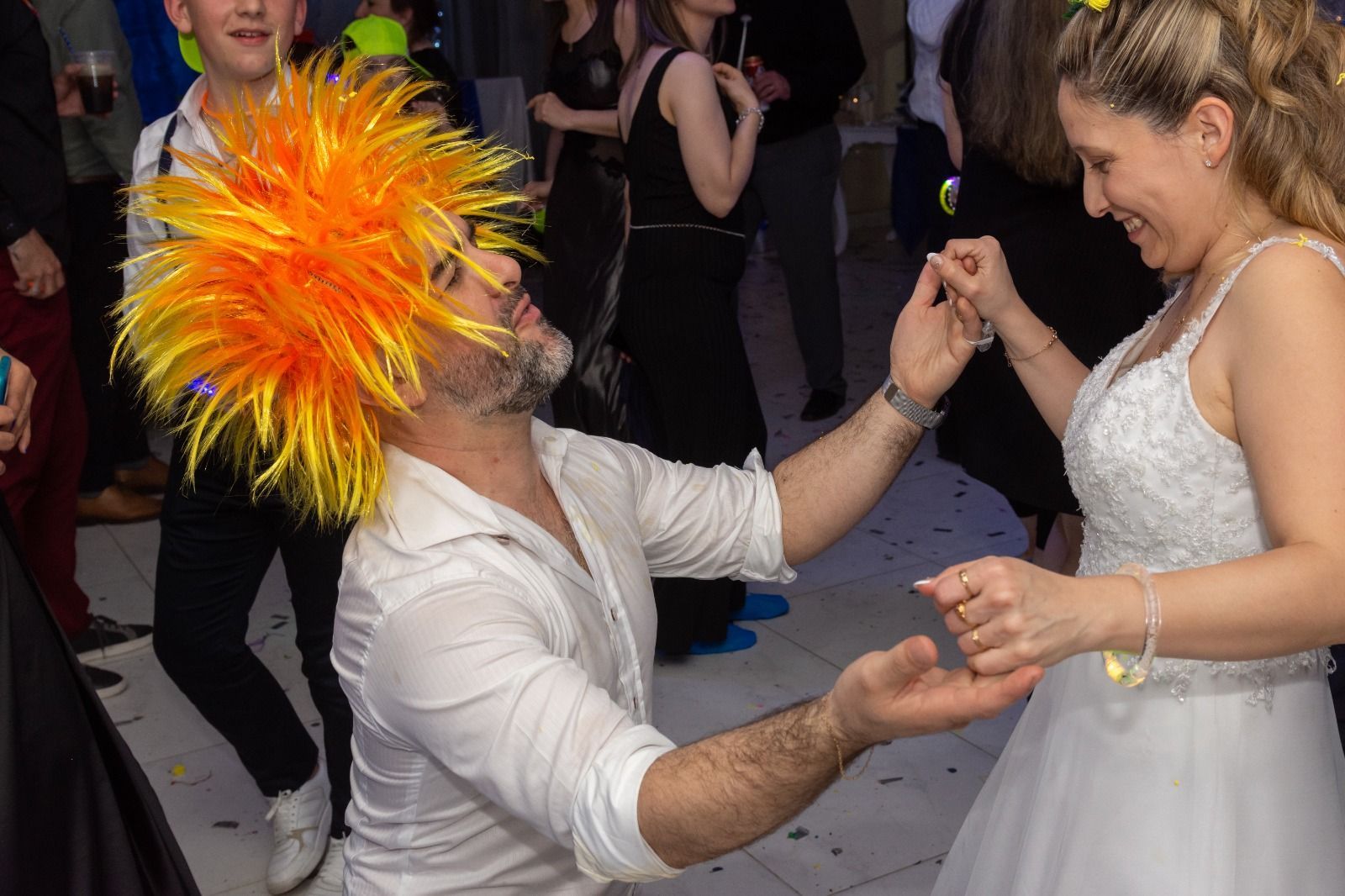 Un hombre con peluca naranja se arrodilla, extendiendo la mano 