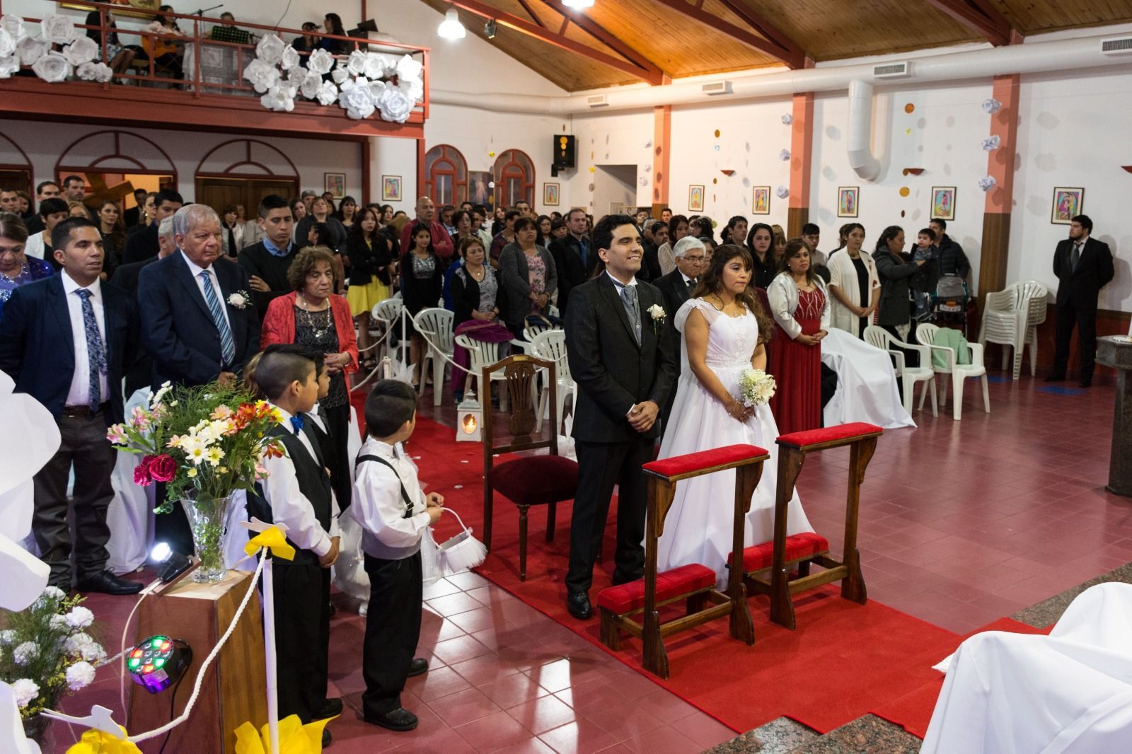 Ceremonia de boda con novios, alfombra roja, invitados en un salón.