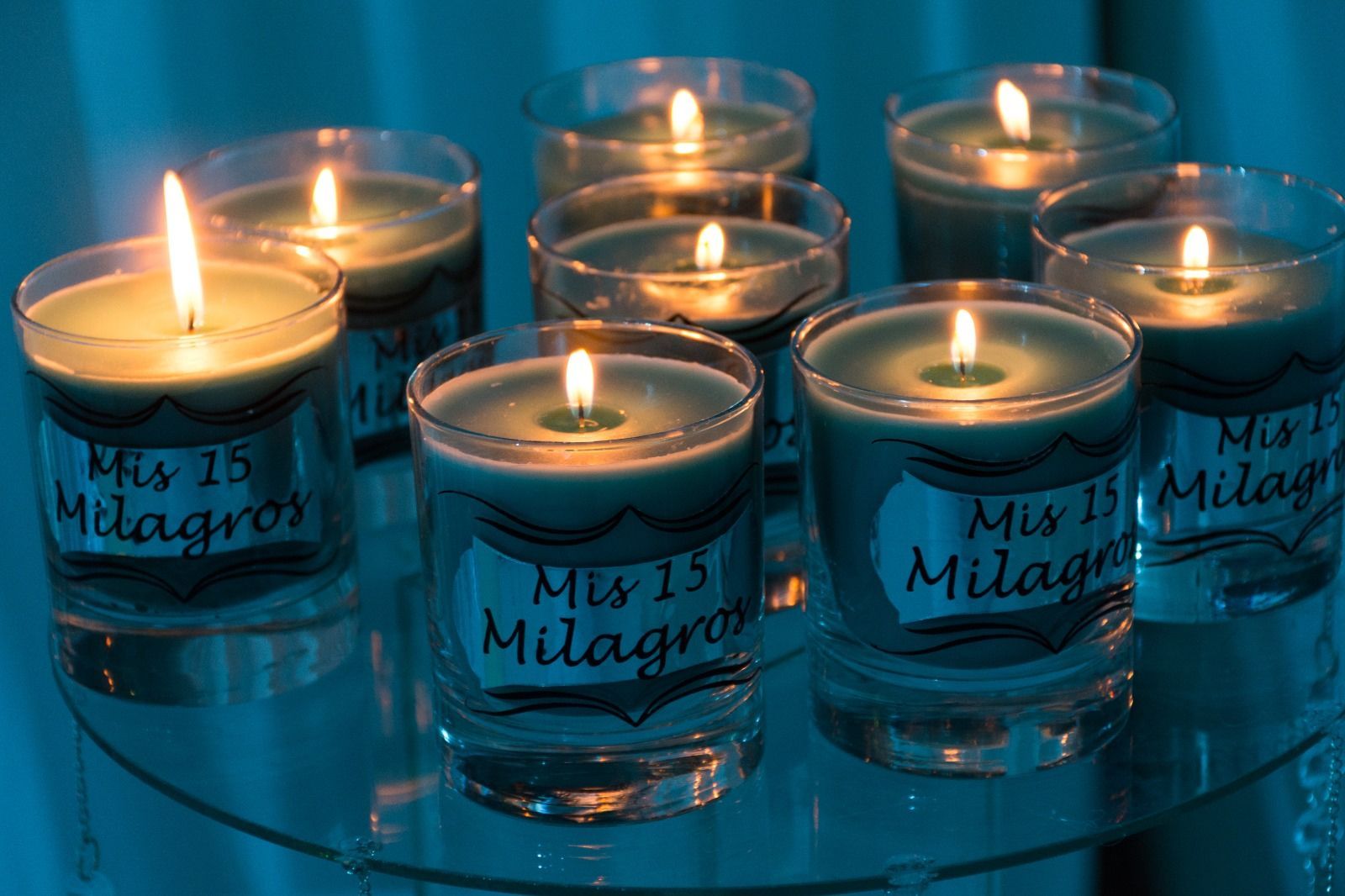 Velas verdes encendidas en porta velas de vidrio sobre una superficie de vidrio