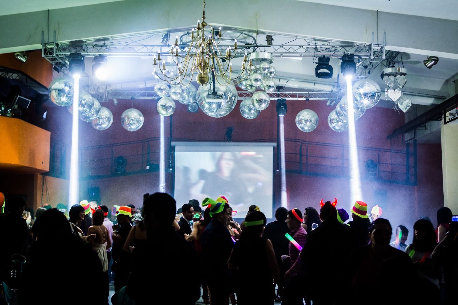Fiesta con bolas de discoteca, luces de escenario y gente con sombreros.