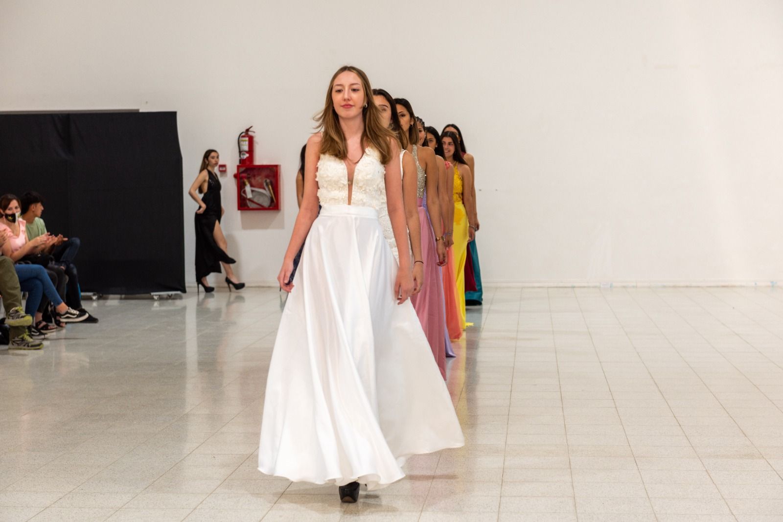 Modelos con vestidos caminan por la pasarela durante un desfile de moda.