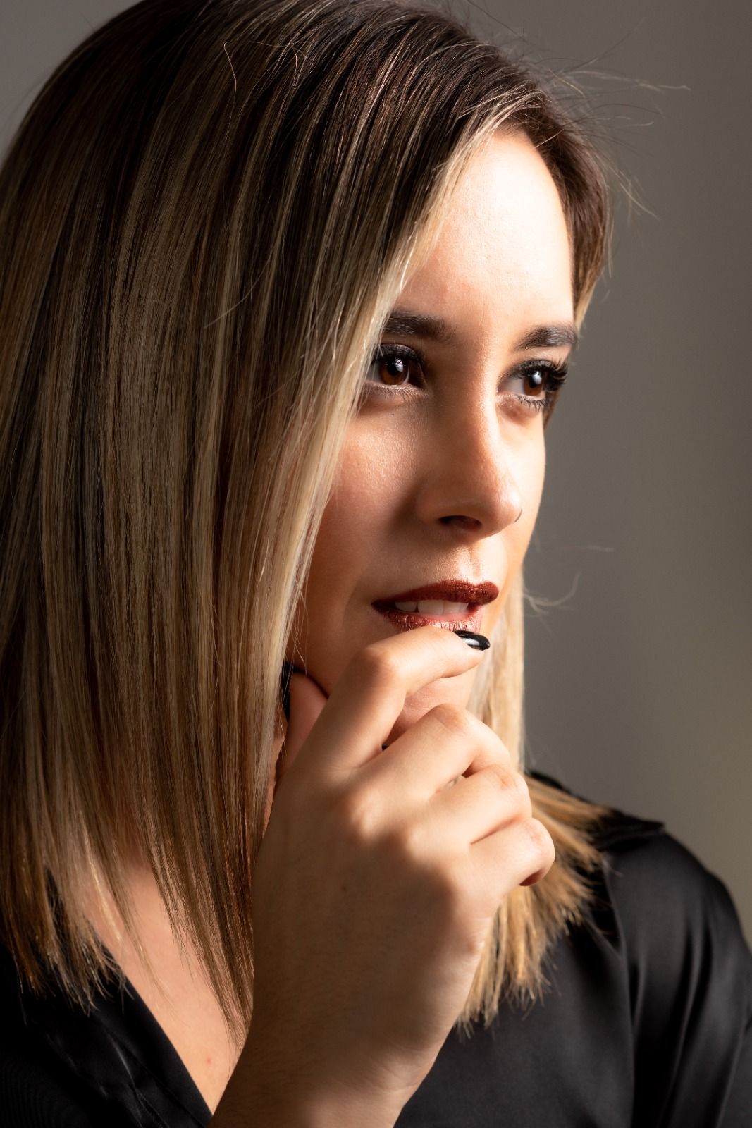 Mujer con cabello castaño claro, lápiz labial oscuro y maquillaje de ojos oscuros