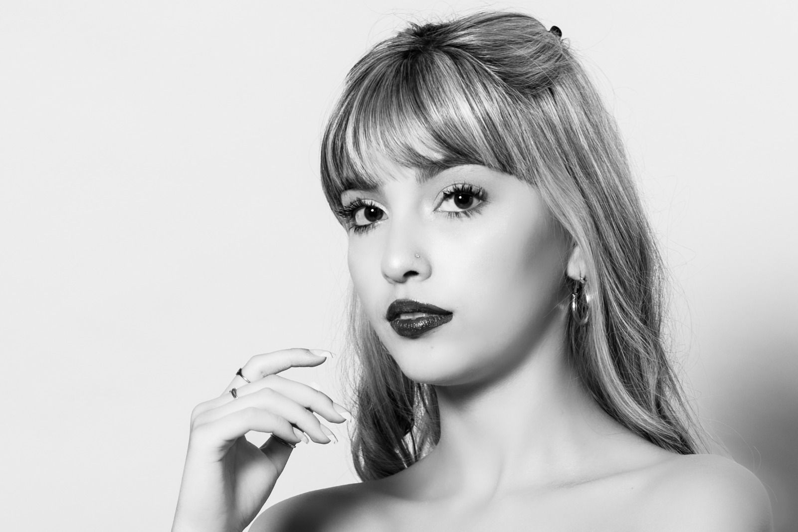 Mujer con lápiz labial oscuro, flequillo y cabello largo, mirando a la cámara.