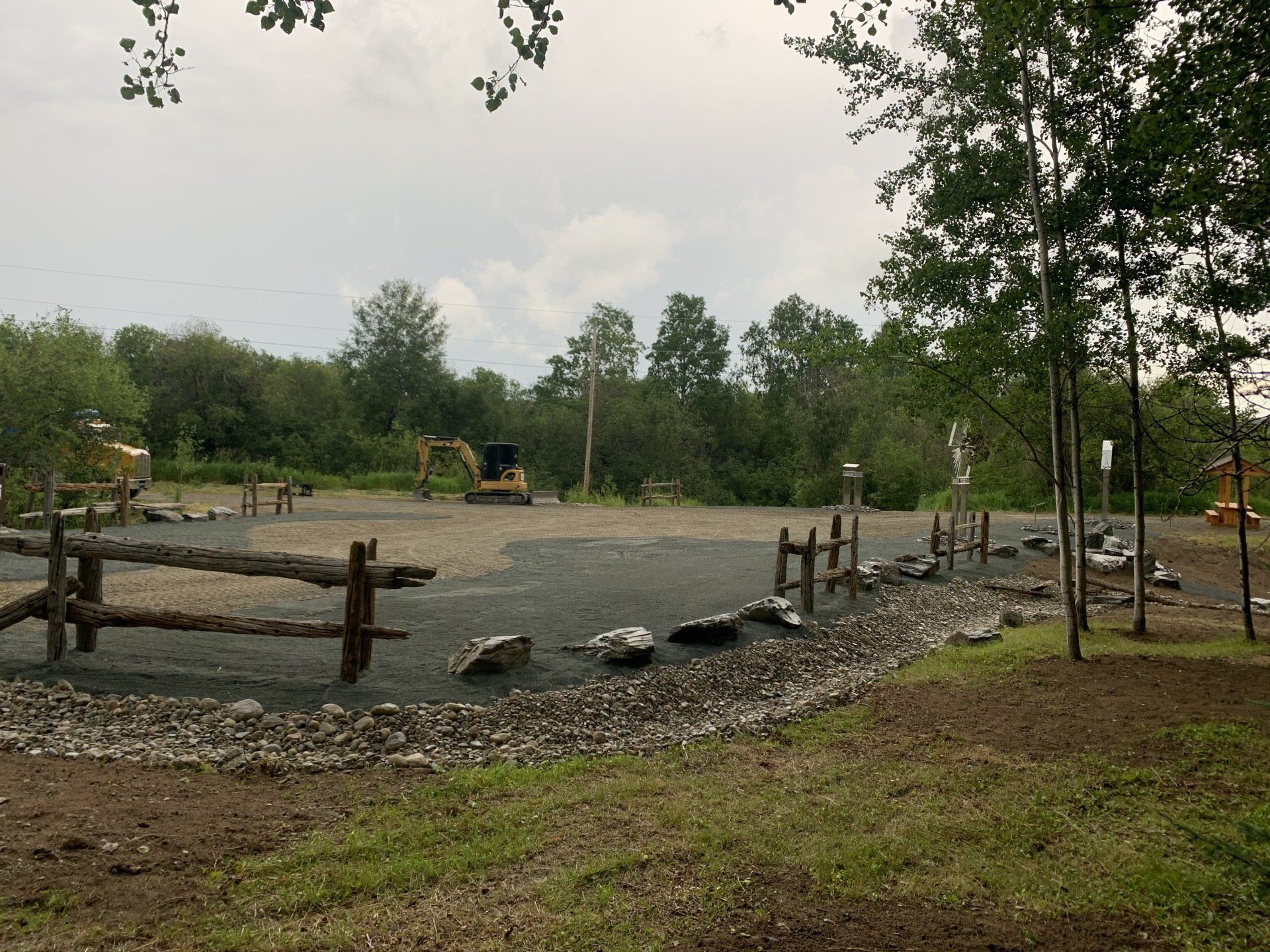 Une aire de jeux avec une clôture en bois et un bulldozer en arrière-plan