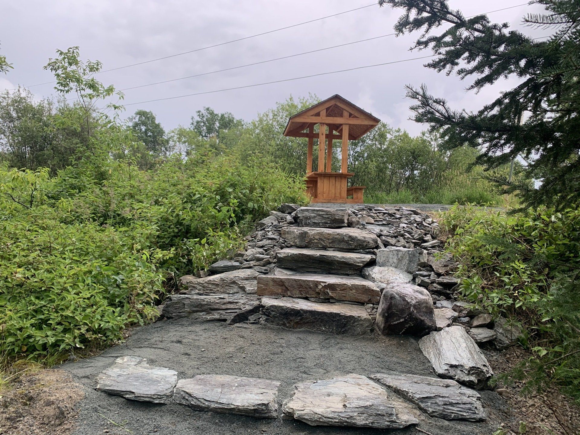 Une passerelle en pierre menant à une structure en bois au milieu d une forêt.