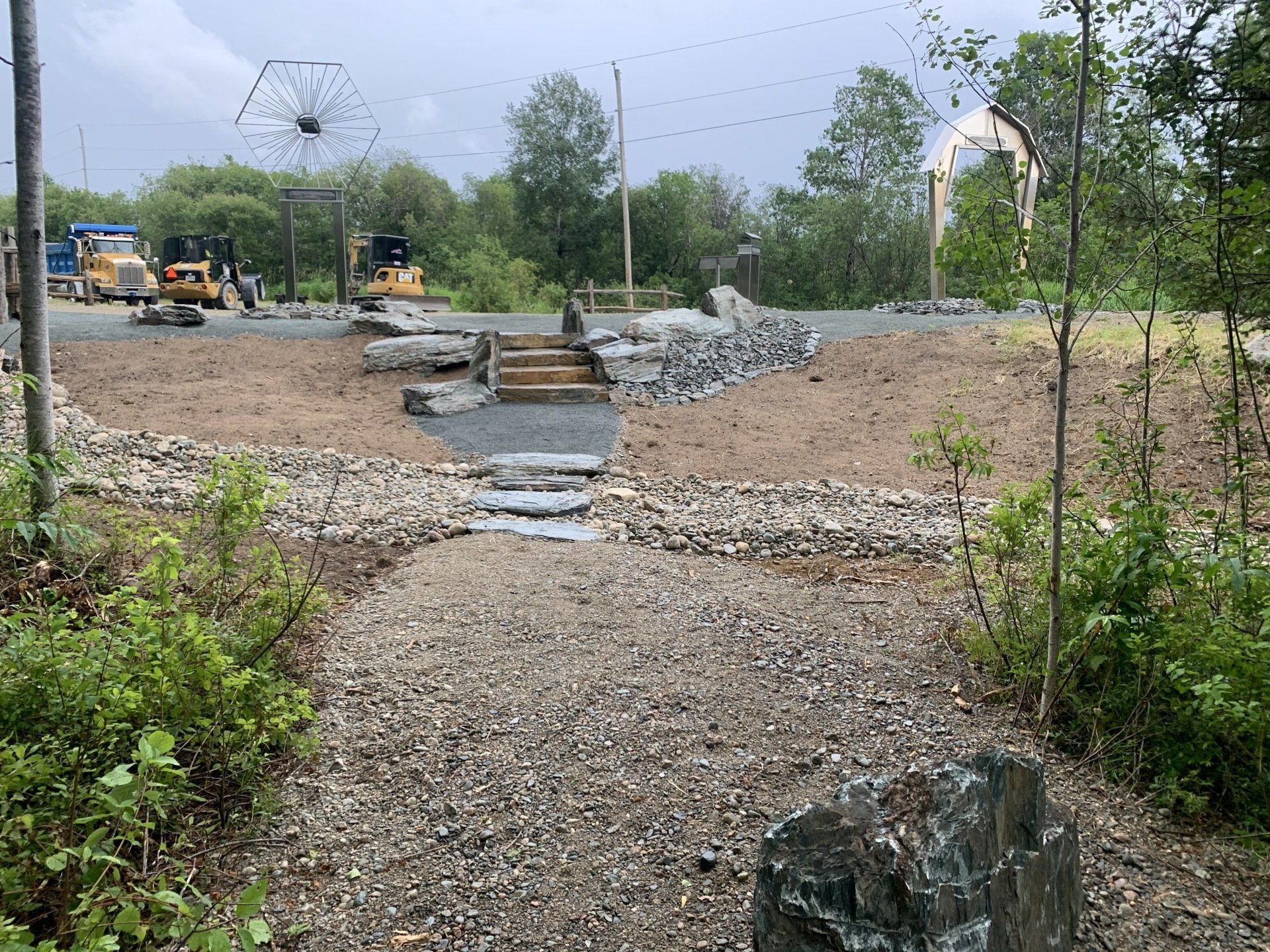 Un chemin de gravier menant à un chantier de construction avec des tracteurs en arrière-plan.