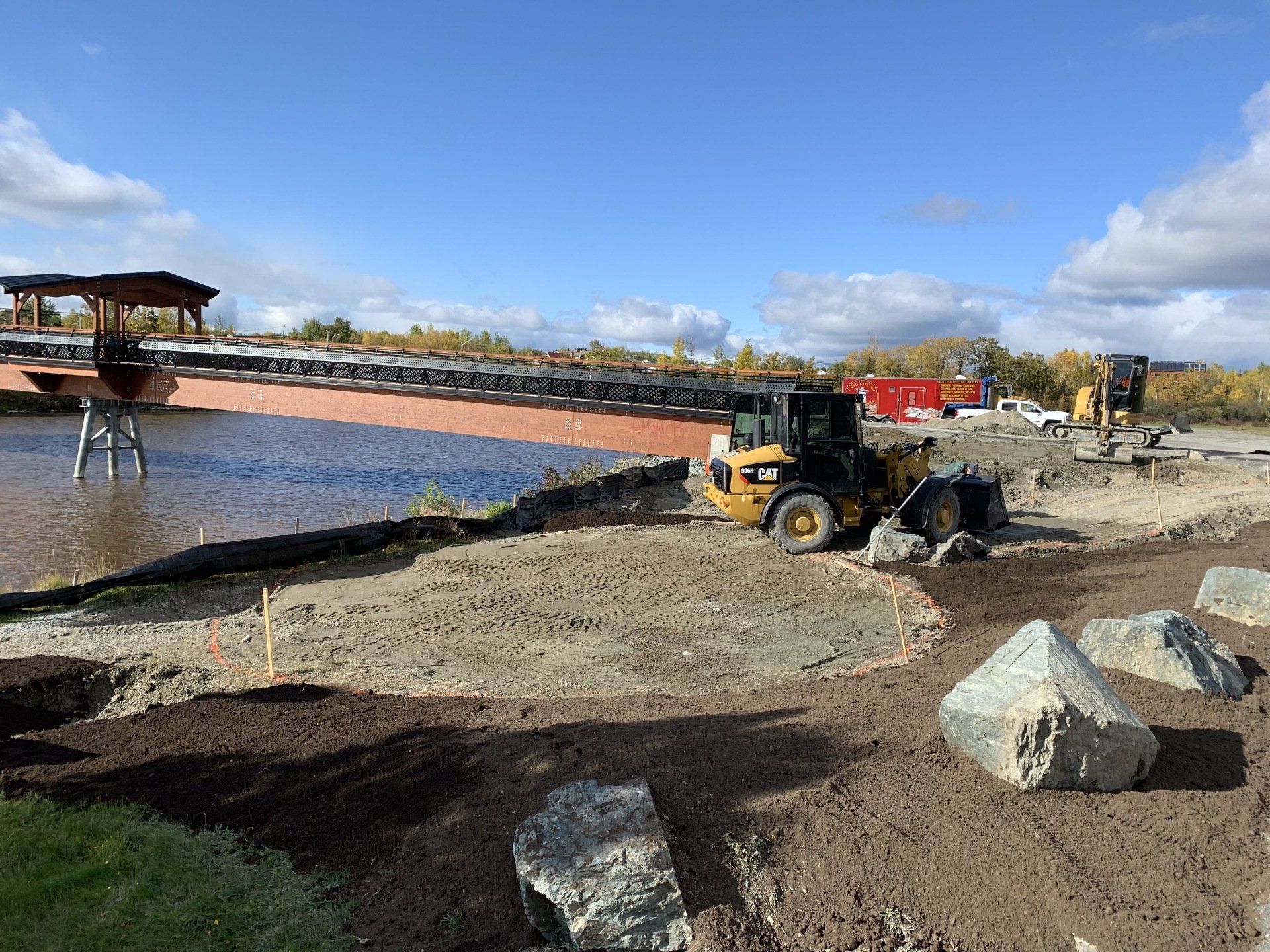 Un chantier de construction avec un pont en arrière-plan et un bulldozer au premier plan.