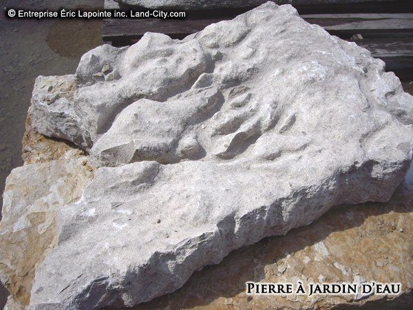 Un gros rocher avec écrit pierre à jardin d eau dessus