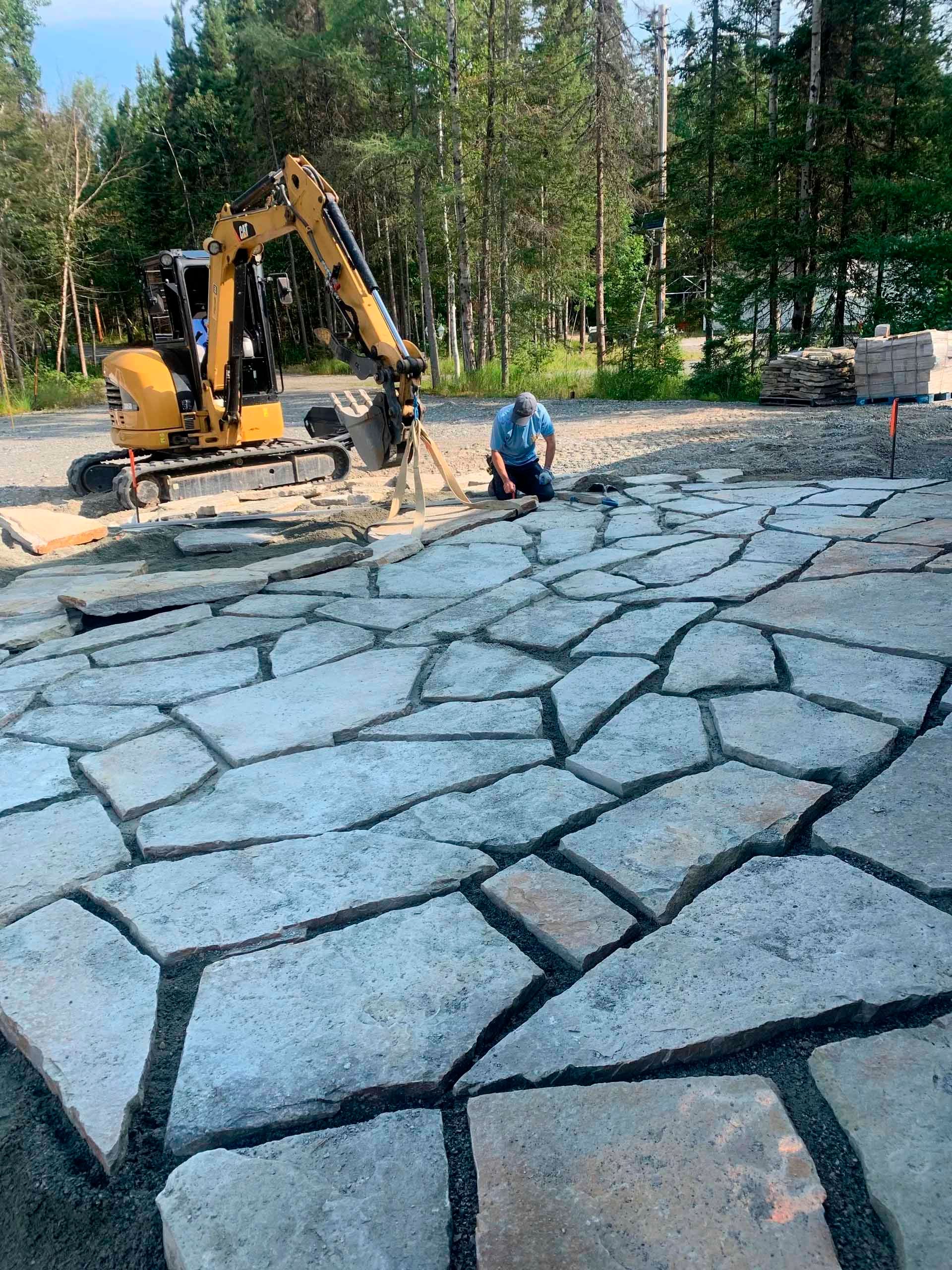 Une excavatrice jaune creuse un trou devant une maison.