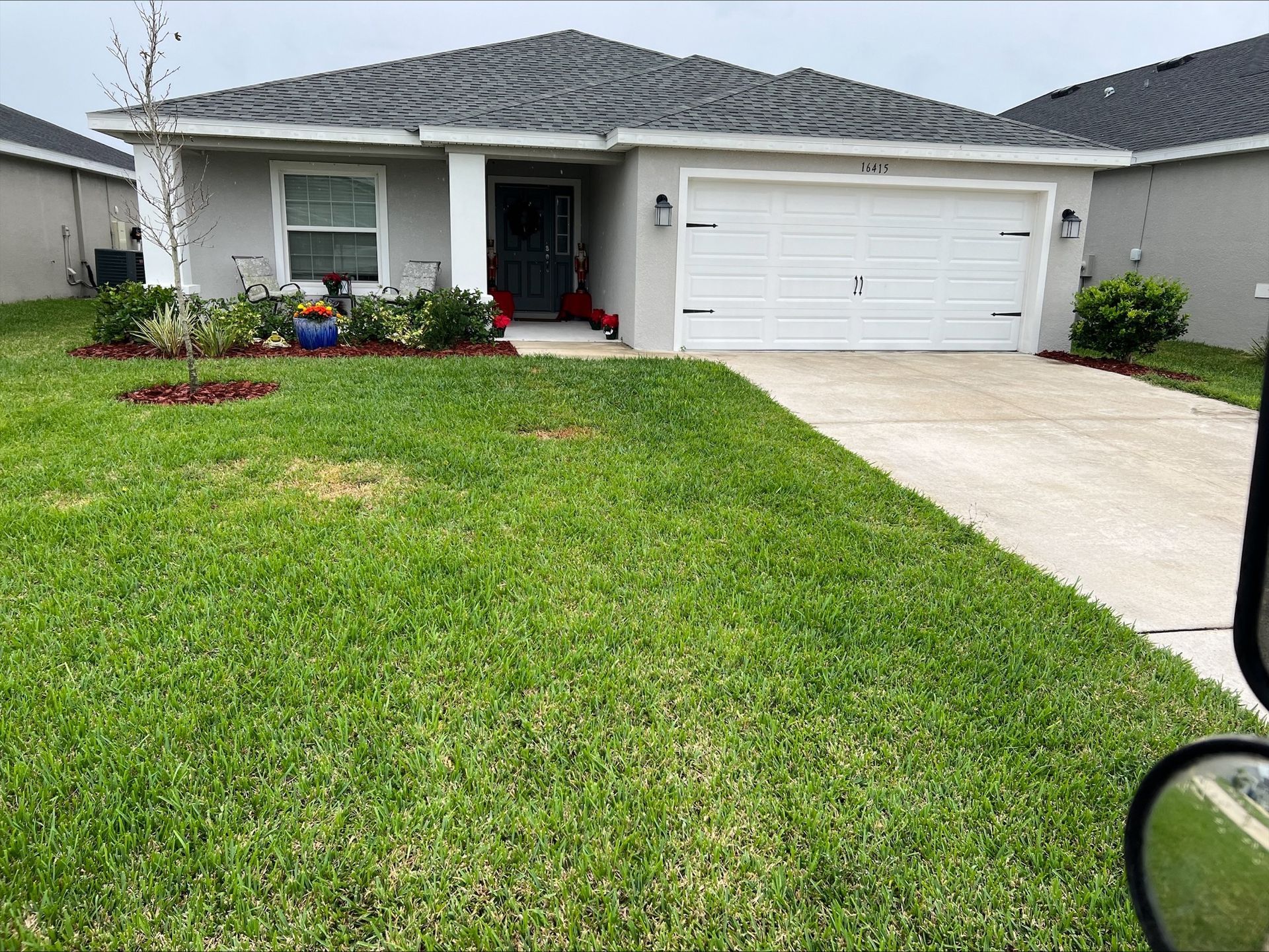 Josh Fertilizing Pro | A house with a lush green lawn and a white garage door.