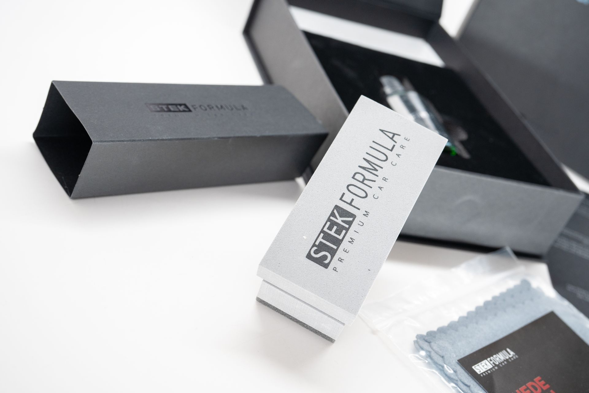 Black and white branded product packaging with a silver box and black sleeve on a white surface