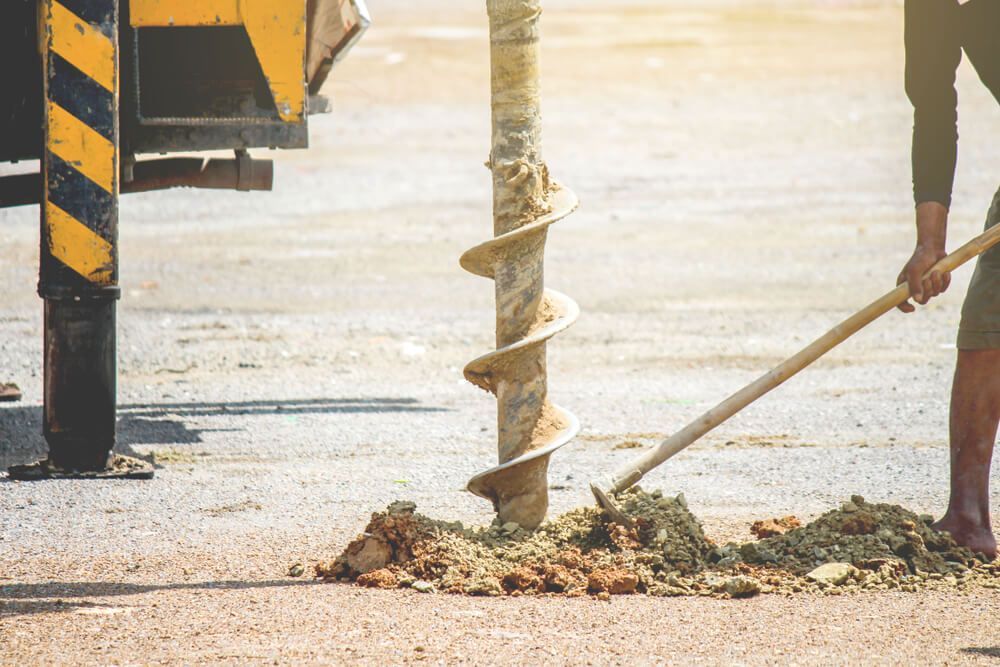A Man is Using a Drill to Dig a Hole in the Ground — Q-Pile Foundations in Noosa, QLD