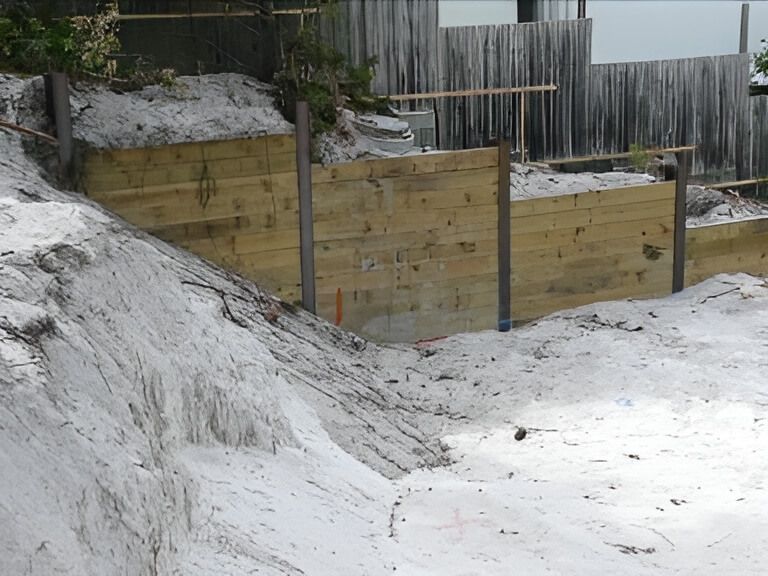 A Wooden Fence is Surrounded by a Pile of Sand — Q-Pile Foundations in Coolum Beach, QLD