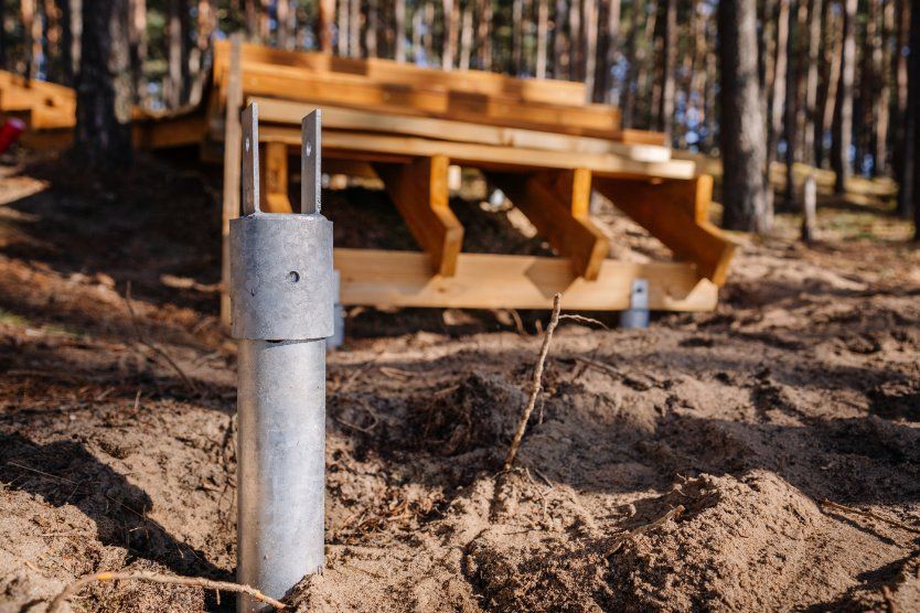A Metal Pole is Sitting in the Sand Next to a Wooden Bench in the Woods — Q-Pile Foundations in Coolum Beach, QLD