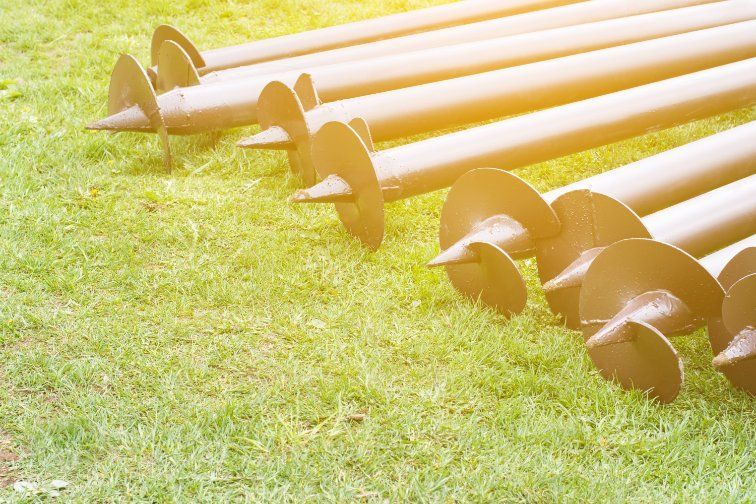 A Row of Metal Screws on Top of a Lush Green Field — Q-Pile Foundations in Caloundra, QLD