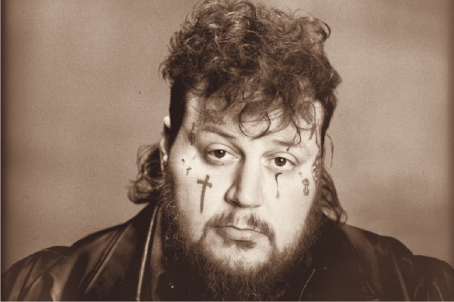 A man with a beard has a cross on his face