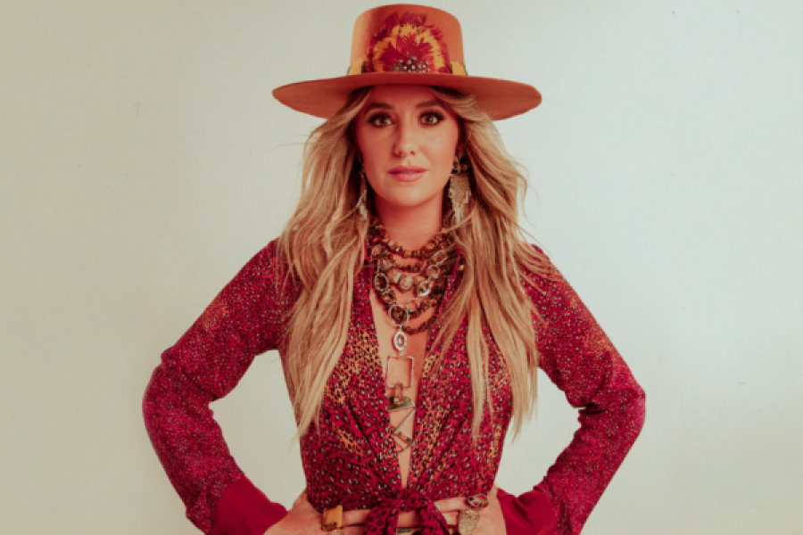 A woman wearing a hat and a red dress is standing with her hands on her hips.