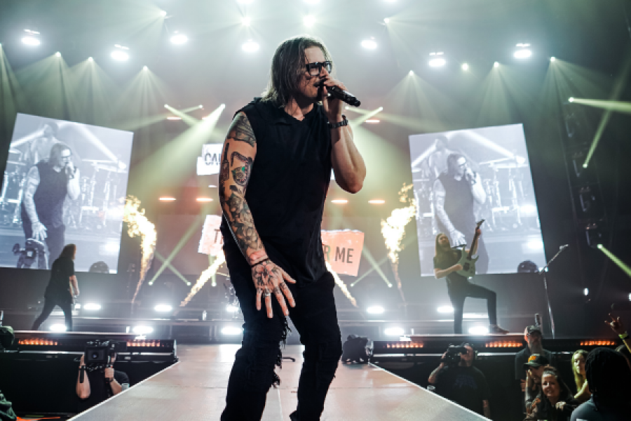 A man is singing into a microphone on a stage in front of a crowd.