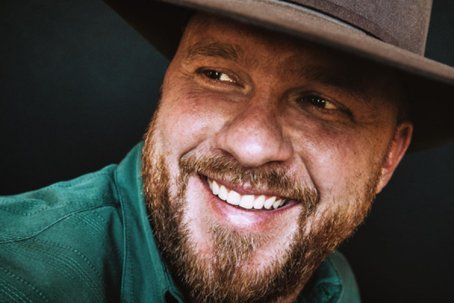 A man with a beard is wearing a hat and smiling.