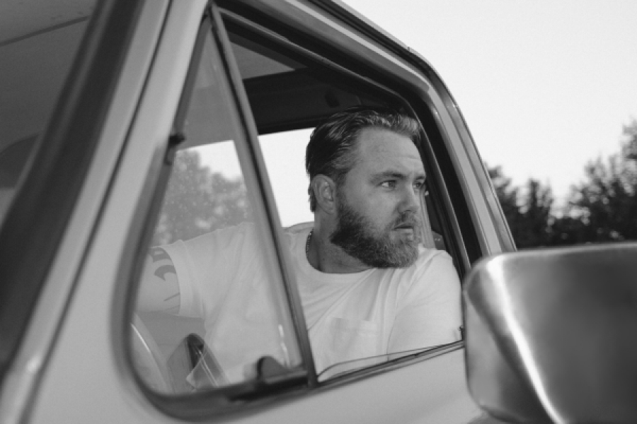 Ernest. A man with a beard is sitting in a car looking out the window.