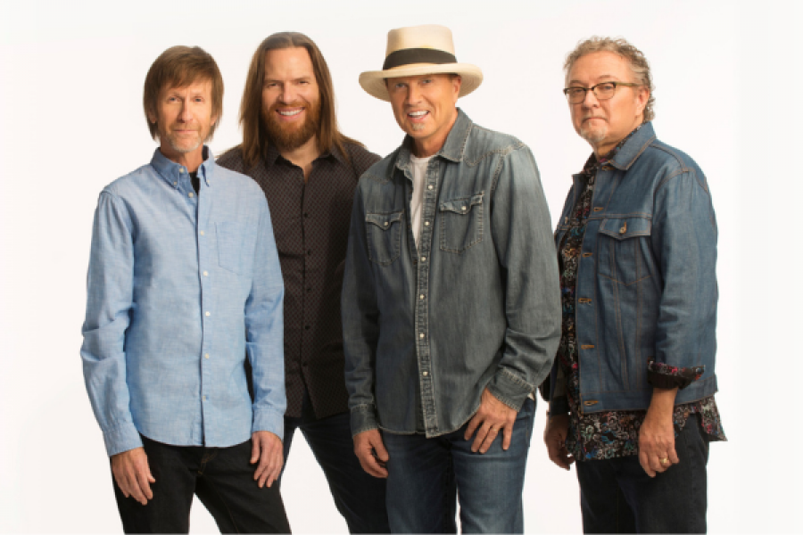 A group of four men standing next to each other on a white background.