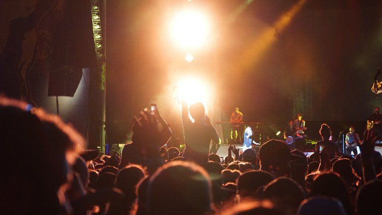 A crowd of people are standing in front of a stage at a concert.