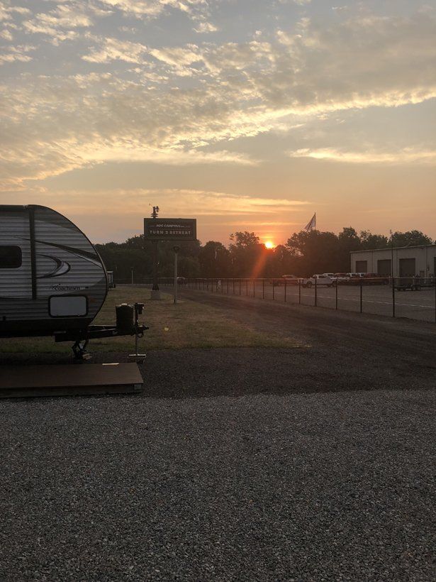 A rv is parked in a gravel lot at sunset.