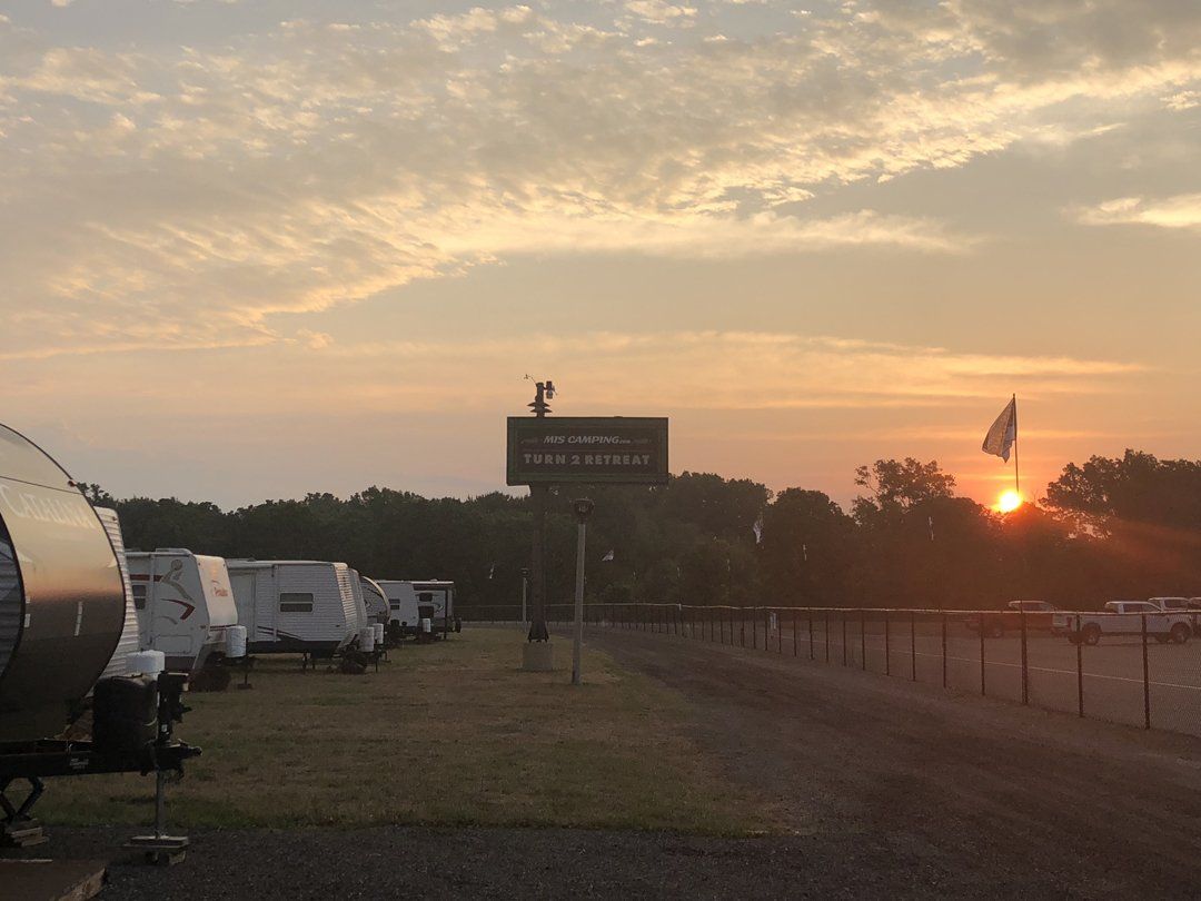 A sunset over a campground with a sign that says welcome