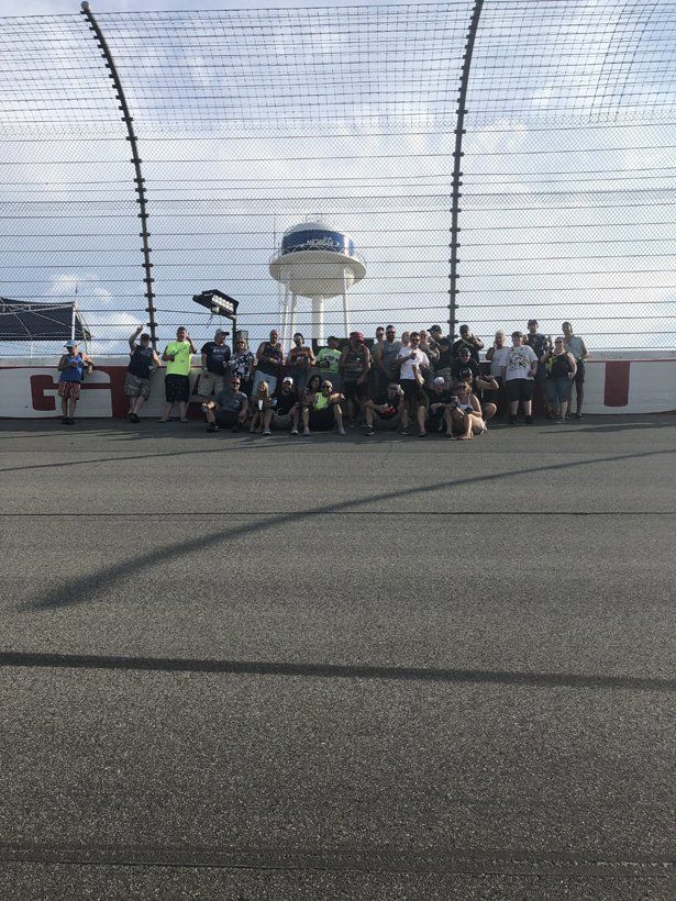 A group of people are posing for a picture on a race track.