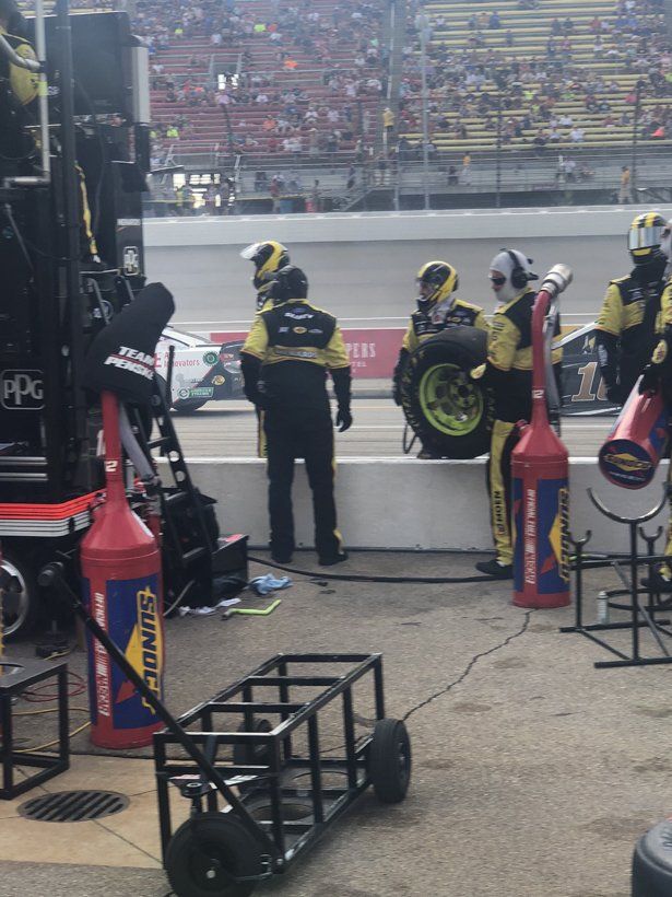 A group of men are working on a race car in a pit lane.