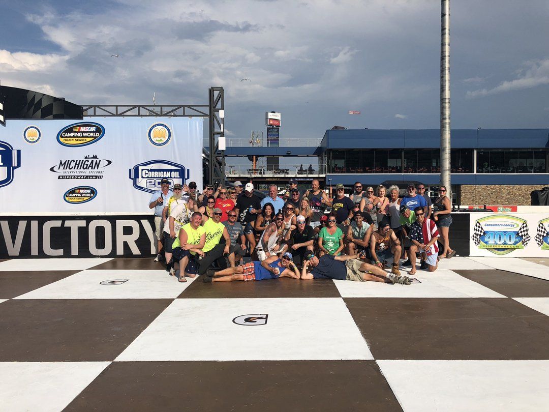 A group of people are posing for a picture in front of a sign that says victory.