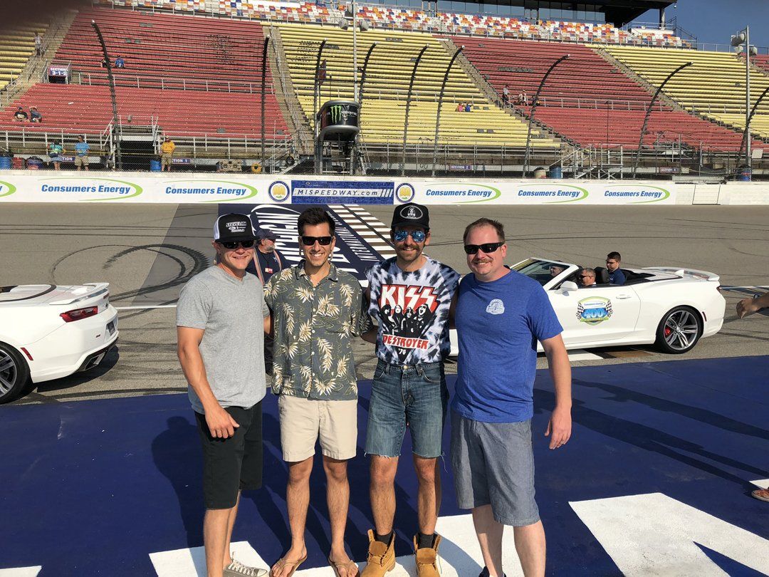 A group of men are posing for a picture in front of a race car.