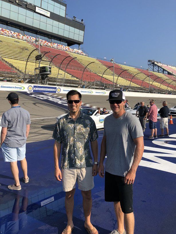 Two men are standing next to each other on a race track.