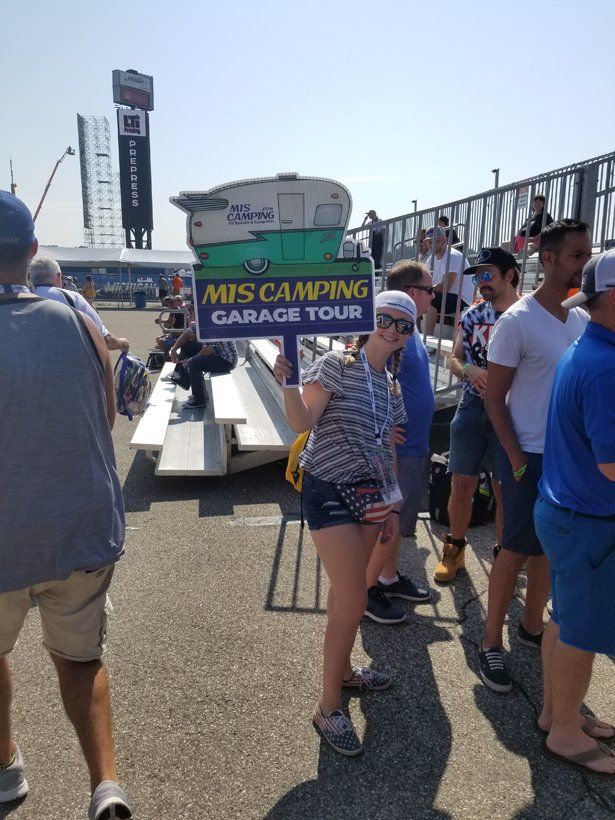 A group of people standing around a sign that says mis camping garage tour