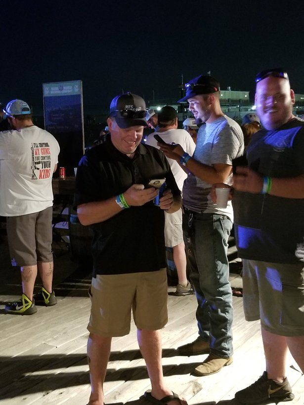 A group of men standing next to each other looking at their phones