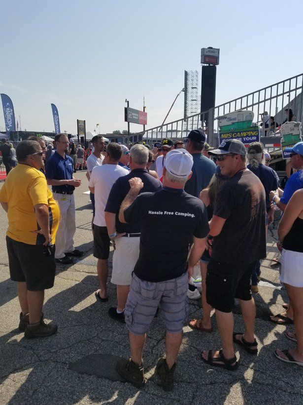 A group of people are gathered in a parking lot with one man wearing a shirt that says ' i love you '