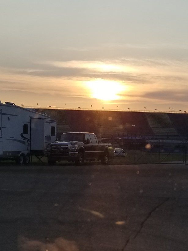 A truck and trailer are parked in a parking lot at sunset
