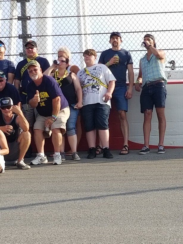 A group of people are posing for a picture in front of a fence.