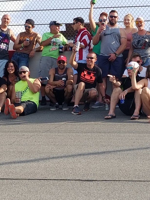 A group of people are posing for a picture in front of a chain link fence.