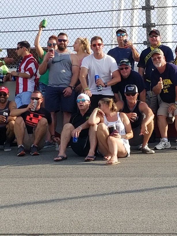 A group of people are posing for a picture in front of a chain link fence.