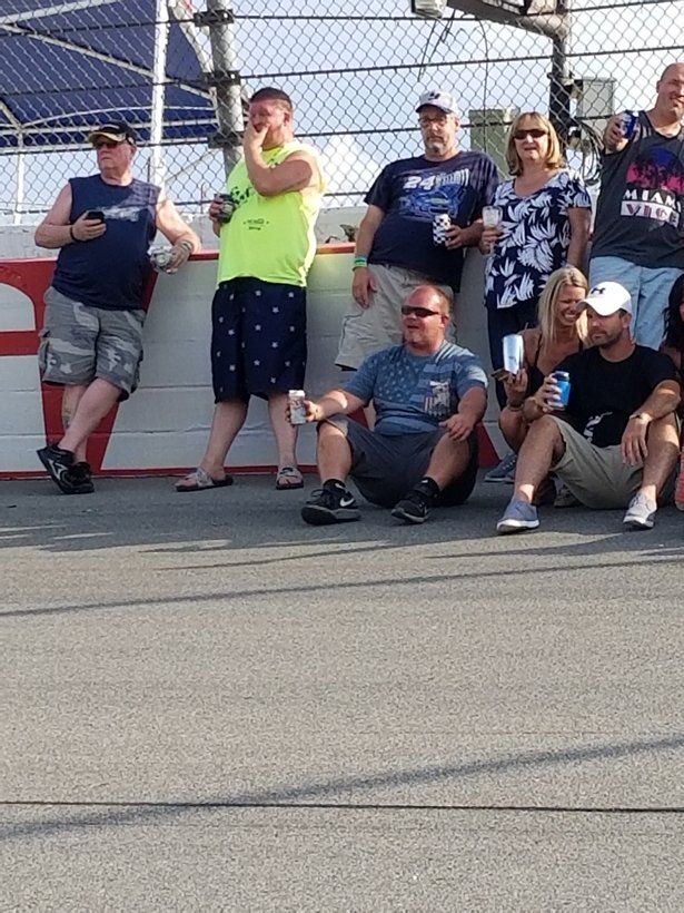 A group of people are sitting on the ground watching a race.
