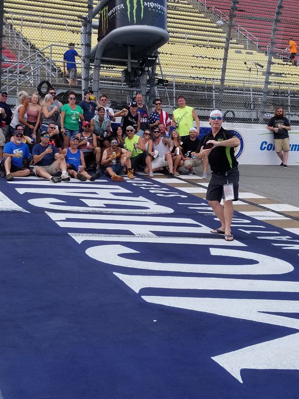 A group of people are sitting on the ground in front of a large sign that says coca cola.