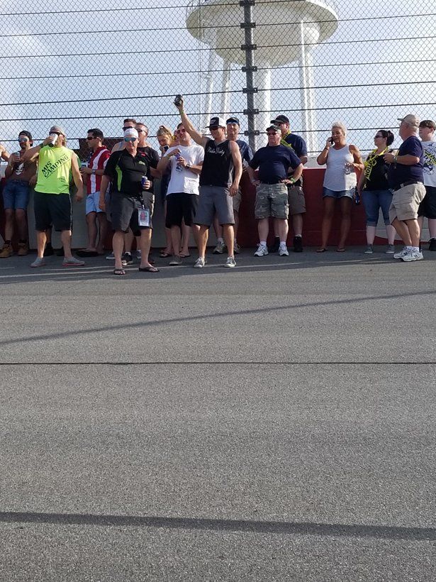 A group of people are standing in front of a chain link fence.