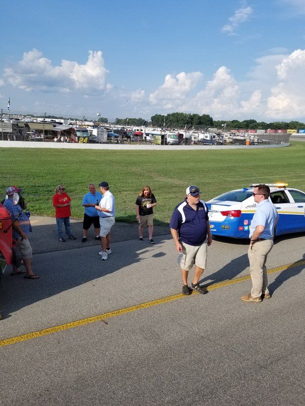 A group of people standing in front of a blue and white police car