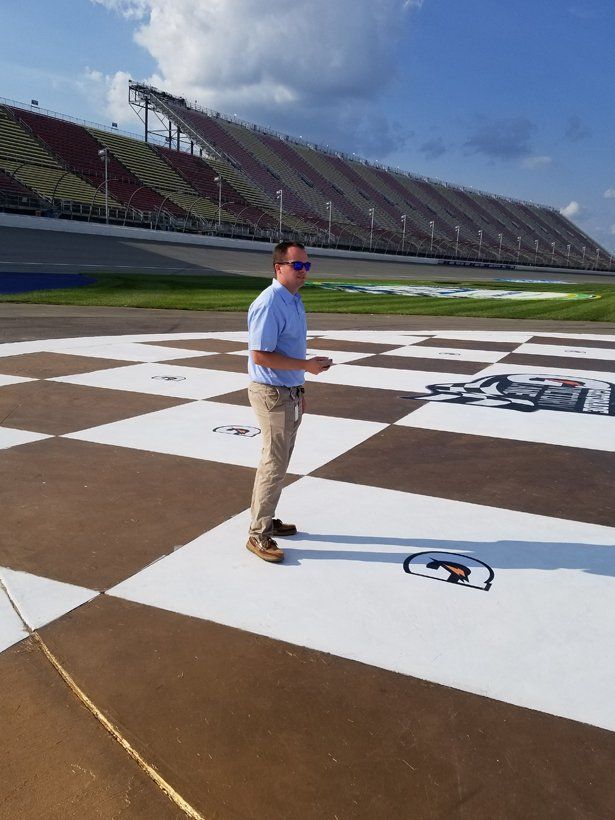 A man is standing on a checkered floor in front of a stadium.