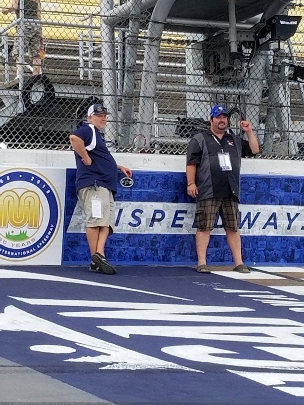 Two men are standing next to each other on a race track.