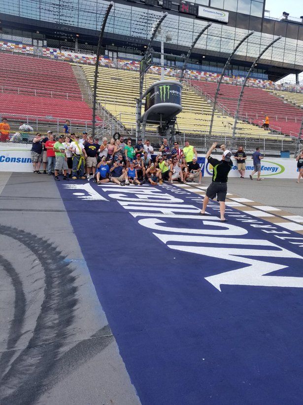 A group of people are posing for a picture on a race track.
