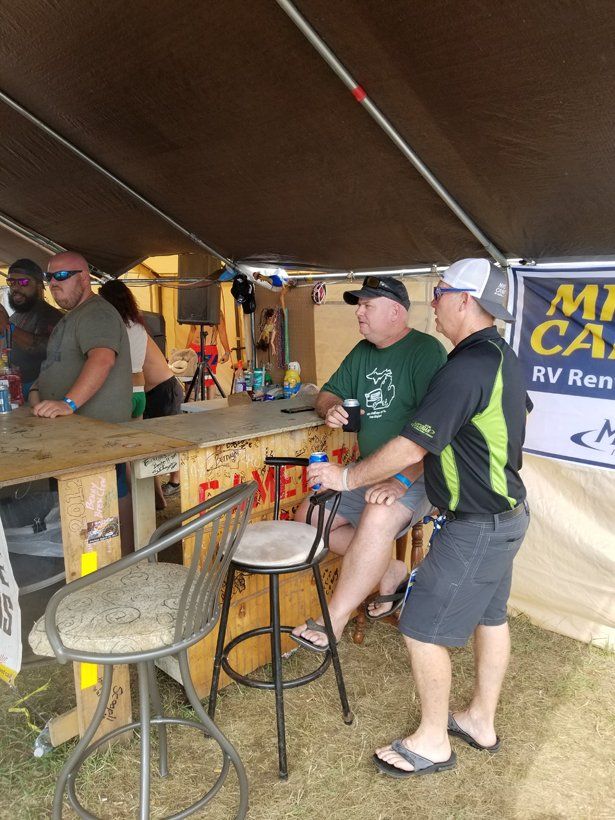 A group of men are sitting at a table under a tent.
